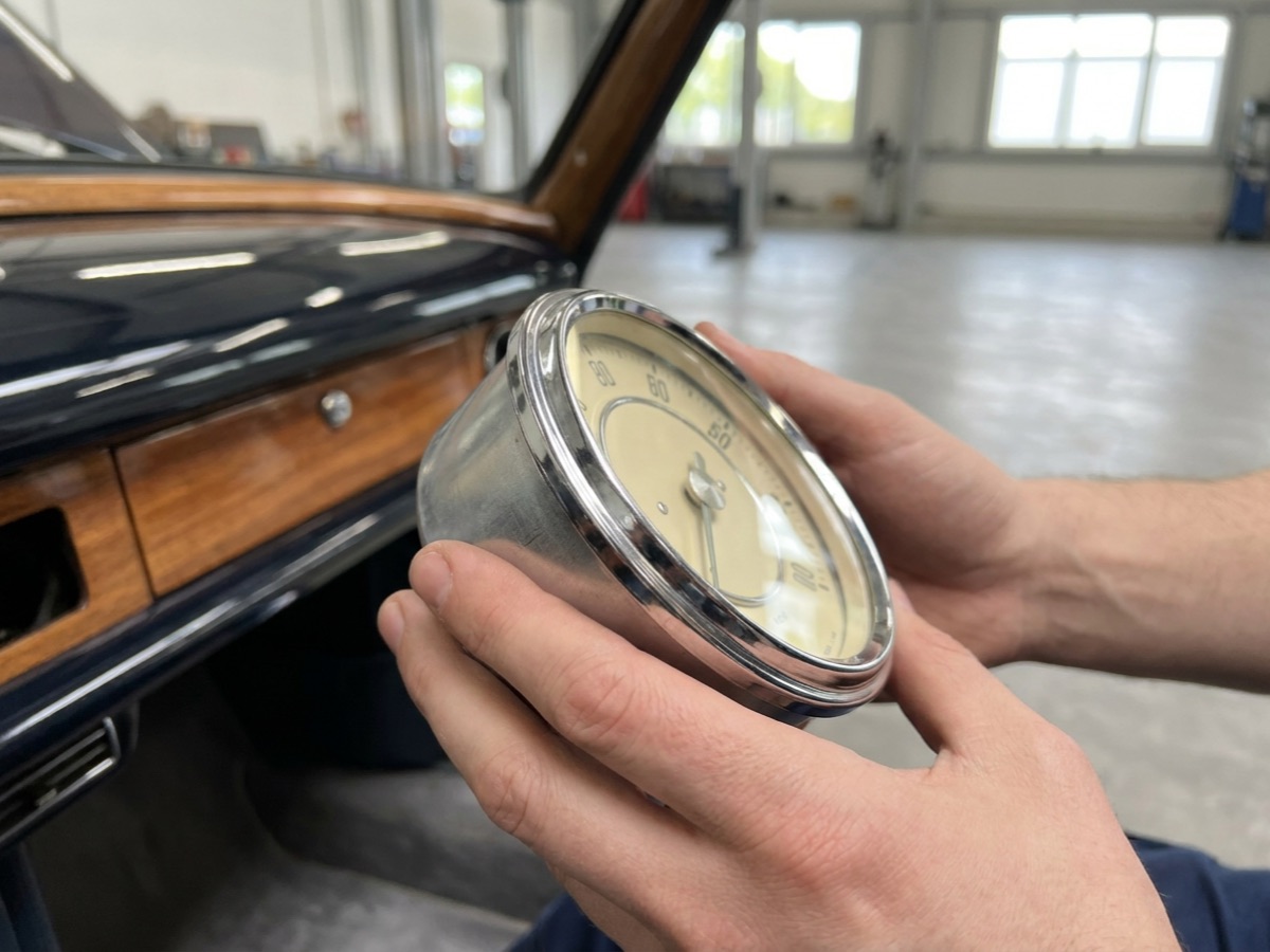 Restauriertes Chrom-Instrument eines Oldtimers vor einem Armaturenbrett mit Holzverkleidung